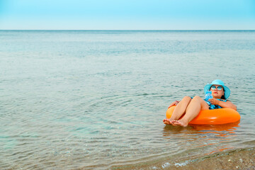 Woman in a straw hat and glasses in the sea in a swimming circle.