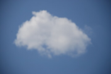 White fluffy oval cloud. A small white cloud floats in a clear light blue sky, it is an elongated oval-rectangular shape. There are no other clouds around it.