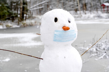 snowman in a protective mask in the snow