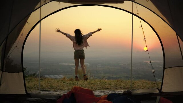 Asians woman caper and watching the beauty of nature in the evening sunset during camping leisure trip,freedom concept , travel
