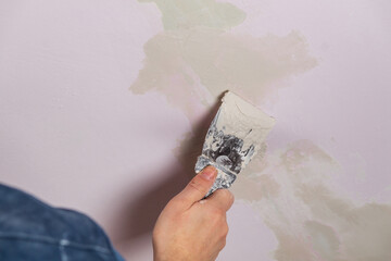 Builder with trowel plastering wall or ceiling. Close-up of the master hand while working.