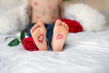 Fototapeta Toddlers feet with lipstick kiss and heart and a red rose next to him obraz