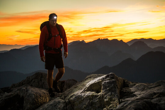 Backpacker hiking at night, using headlamp on rocky terrain.