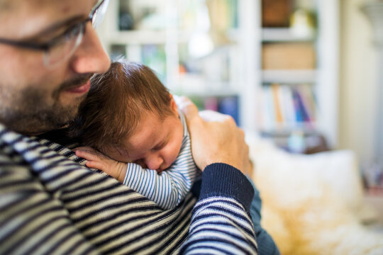 Father embraces his newborn son at home.