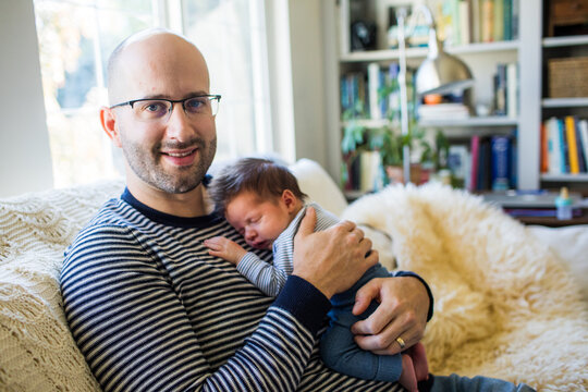 Happy father holds his newborn son at home.