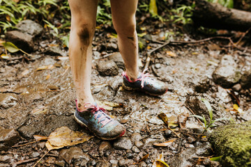 Close up of young girls muddy shoes and legs while hiking in Hawaii
