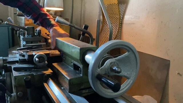 a man is working at a lathe and sharpening a part