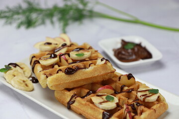 Breakfast waffles with bananas, chocolate spread, apples and toasted almonds. Front view