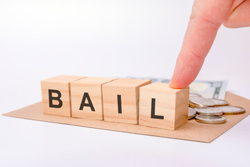 four wooden cubes with word BAIL on gray working board.
