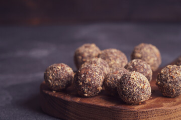 Healthy homemade energy balls on wooden plate. Vegan candies, sweets made of nuts and dates.