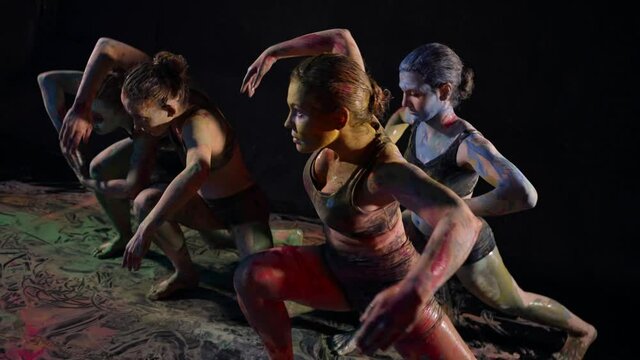 female dancing group is rehearsing dance with paints, four young women are dancing in darkness