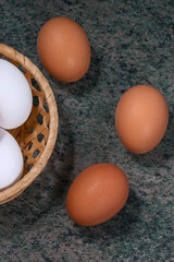 several fresh chicken eggs in a straw basket on a wooden background. Healthy eating concept.