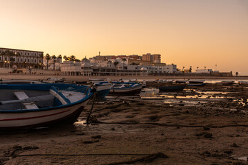 Boats docked in La Caleta beach at low tide at sunrise, Cadiz, Andalusia, Spain