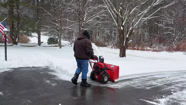 A man uses his snowblower to clear 6 inches of heavy wet snow from the driveway in Windsor in Upstate NY.