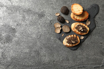 Delicious bruschettas with truffle sauce on grey table, flat lay. Space for text