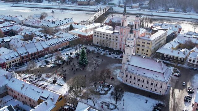 Aerial 4K rotating footage of snowy Kaunas oldtown with Christmas tree and market in city hall square