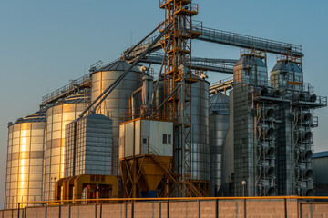 Fototapeta na wymiar A large modern plant for the storage and processing of grain crops. view of the granary on a sunny day against the blue sky. End of harvest season.