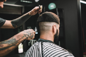 Young man client at barbershop getting haircut hipster
