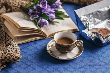 Coffee in bed, romantic morning. Flowers, an open book, a cup of coffee and chocolate. Home cozy interior, lifestyle. selective focus