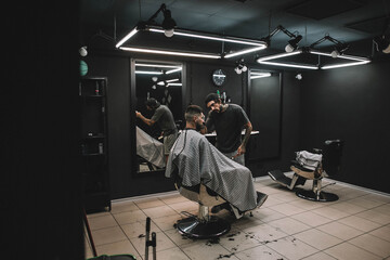 At barbershop young man getting haircut hipster beard black salon