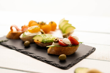 Delicious snacks, sandwiches, crostini, canape, antipasti with salmon avocado, tomatoes, cream cheese, mozzarella for party ,birthday . The concept of healthy food and mediterranean cuisine.