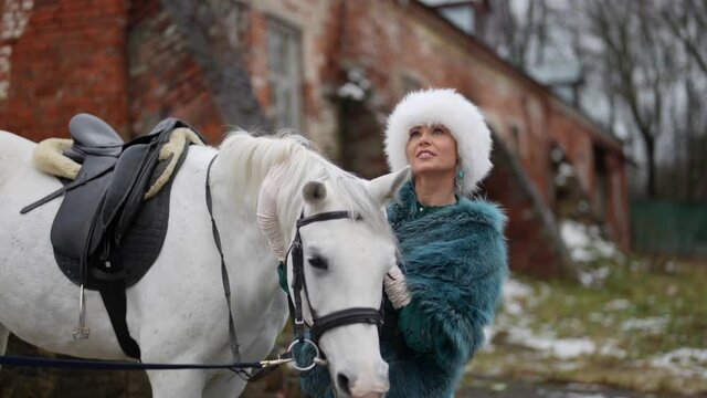 stunning woman and white horse outdoors in nature, lady is embracing steed