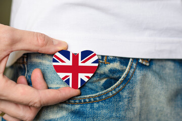 Patriot of the UK! Wooden badge with United Kingdom flag in the shape of a heart in a man's hand.