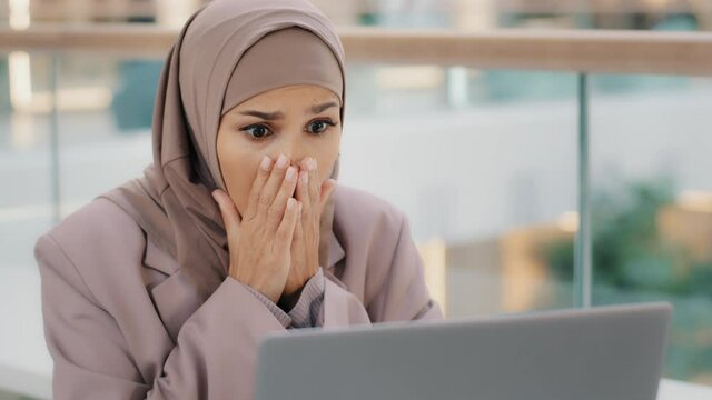 Sad muslim girl student in hijab looking at laptop screen reading email shocked by bad news frustrated businesswoman worries about financial problems gets failed exam results college dropout lost job