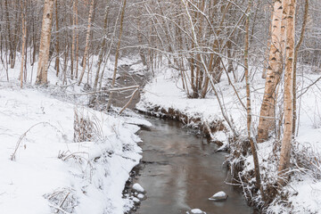 small stream in the snowy forest.and snow covered trees. Winter nature.