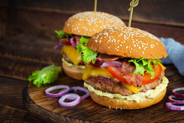 Delicious beef hamburger with bacon slice, cheese, lettuce and tomato. Tasty fastfood burger