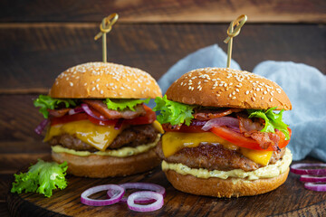 Delicious beef hamburger with bacon slice, cheese, lettuce and tomato. Tasty fastfood burger