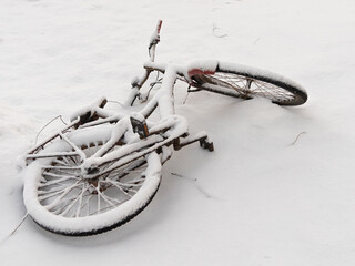 Bicycle on the ground covered with snow, after a snowfall