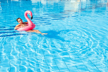 Young women pool. Happy young sexy girl in bikini swimsuit with pink inflatable flamingo float in blue water. Travel holidays vacation. Beauty, wellness, lifestyle.