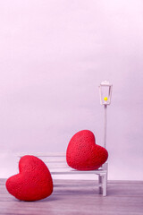 Pair of hearts on a white bench on a light background. Love concept, closeup with copy space. Vertical Format