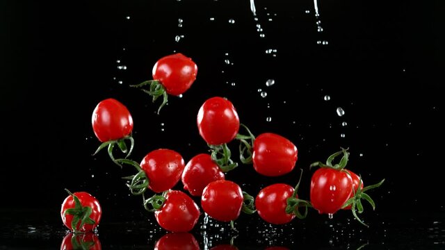 Super slow motion of falling cherry tomatoes with water splashes. Filmed on high speed cinema camera at 1000 fps.