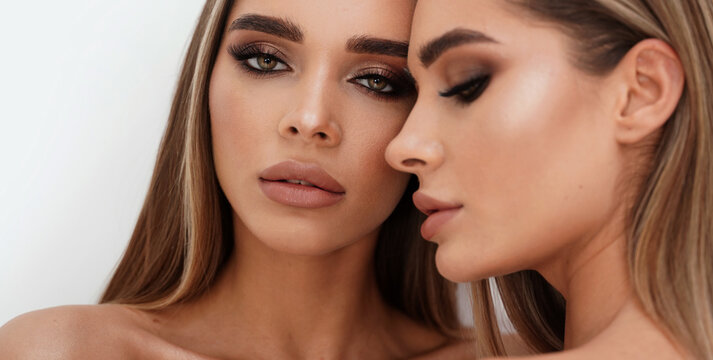 Beauty portrait of two beautiful young women with glowing glamour makeup and long straight hair. Aesthetic medicine concept.