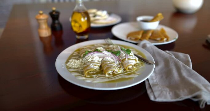 Delicious green Mexican enchiladas, and quesadillas on brown table