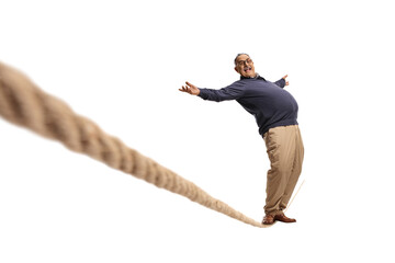 Full length portrait of a mature man standing on a tightrope and leaning backwards