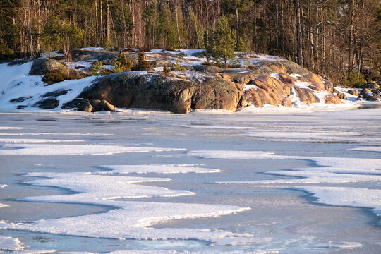 A view of a small island across a frozen river during a sunny winter day.