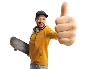 Happy guy in a yellow sweatshirt with a skateboard gesturing thumbs up