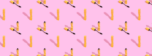 Creative pattern made with gold mascara on pink background. Minimal make up artist, beauty concept
