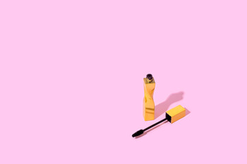 Gold mascara on pink background. Minimal make up artist beauty concept. Copy space
