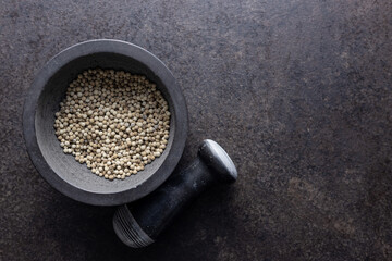 Whole pepper spice. White peppercorn grain in mortar