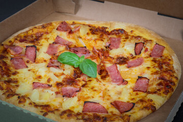 Round baked pizza in a craft box on a black