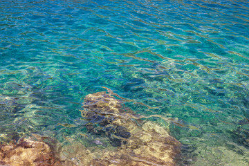 Crystal clear waters of the sea with gentle ripples that reveal the rocks in the background and a large number of shades of turquoise, blue, green and ocher colors creating a suggestive and luminous s