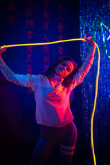 Studio Portrait of a young fashion woman dancing. Style. High fashion girl model in stylish clothes in colorful neon lights portrait. Sexy woman in trendy dress under pink and purple light at studio.