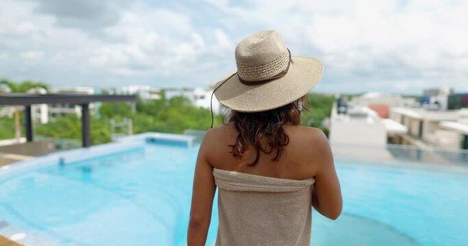Beautiful woman on poolside taking off her towel in slow motion