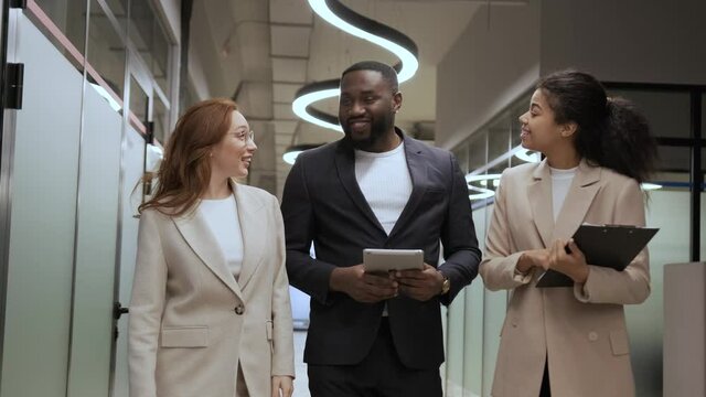 stylish employees in business suits walk in the office and communicate amicably. multi ethnic team