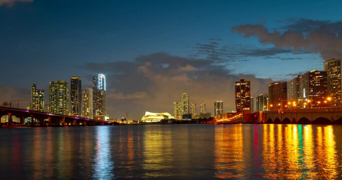 Miami panorama time lapse. Night sky timelapse on Miami beach city. Time lapse of sunset on cityscape sky and clouds moving with water ripple reflection. MacArthur downtown, Causeway city.