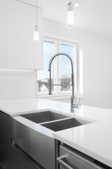 A stainless steel apron sink with a marble counter top, chrome faucet, and a view towards an empty...